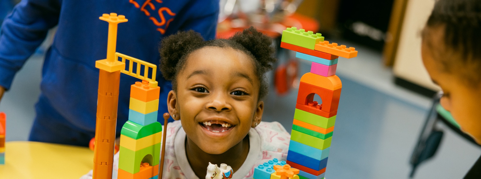 YWCA educational programs slider image of young girl smiling playing with blocks